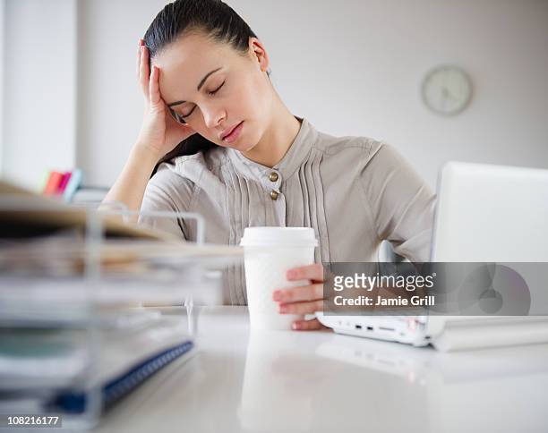 woman exhausted at desk with coffee - exaustão imagens e fotografias de stock