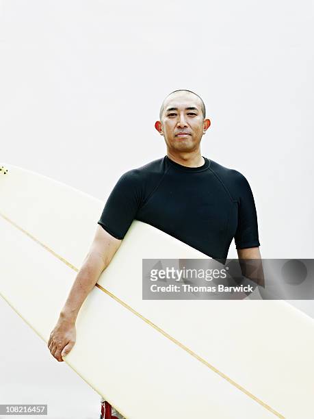 man wearing rash guard holding surfboard - surf life saving stockfoto's en -beelden