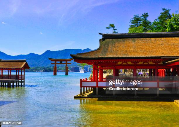 the torii gate and temple buildings on the sea of itsukushima shrine (厳島神社) during low tide at sunset in miyajima (宮島), hiroshima, japan. - 宮島 stock-fotos und bilder