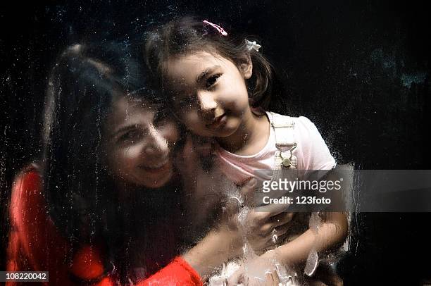 mother holding daughter behind wet and rainy window - girl rain night stock pictures, royalty-free photos & images