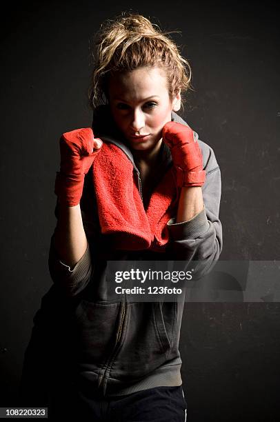 young woman boxer with towel around neck wearing boxing gloves - studiofoto stock pictures, royalty-free photos & images