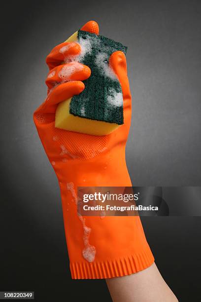 rubber gloved hand holding cleaning sponge - woman squeezing orange stockfoto's en -beelden