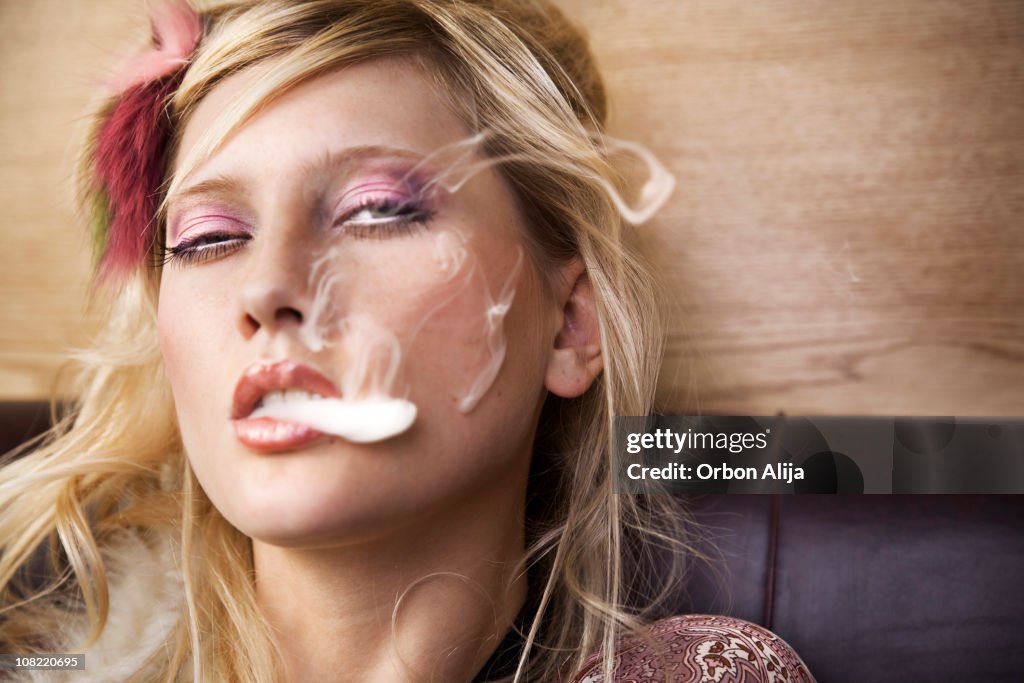 Young Woman Blowing Smoke From Mouth with Eyes Rolling