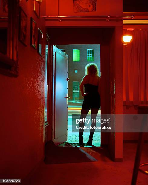 prostitute standing in nightclub doorway looking out - bordello 個照片及圖片檔