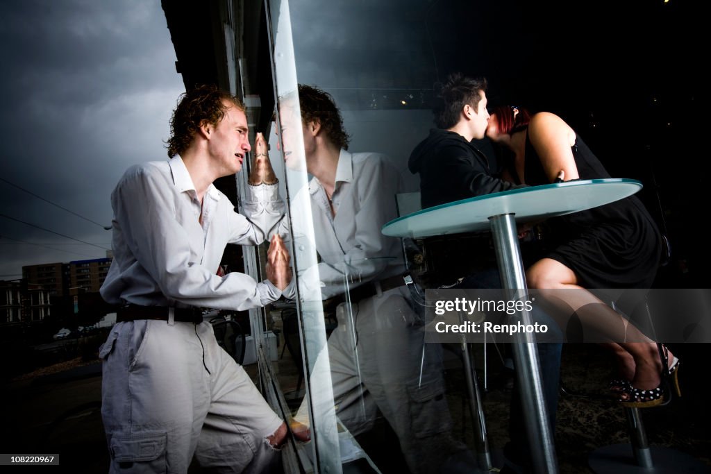 Man with broken heart watching his girlfriend kiss another guy