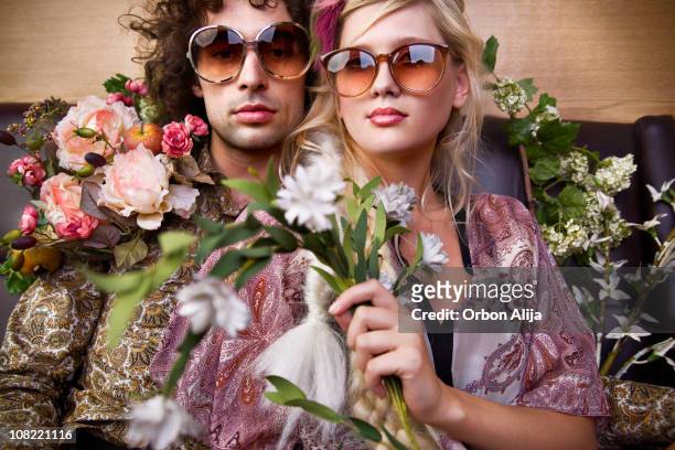 junge hippie mann und frau holding blumen - 1970s fashion stock-fotos und bilder