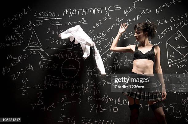 woman throwing shirt off in front of blackboard - leren rok stockfoto's en -beelden