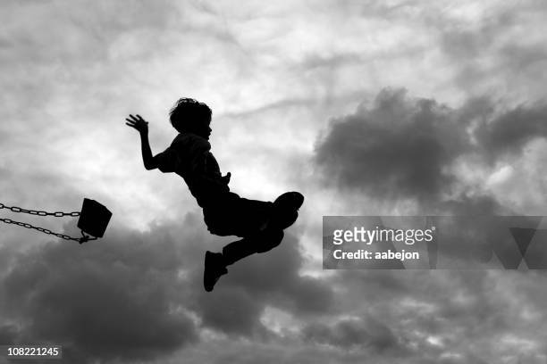 silhouette of little boy jumping off swing - play off stock pictures, royalty-free photos & images