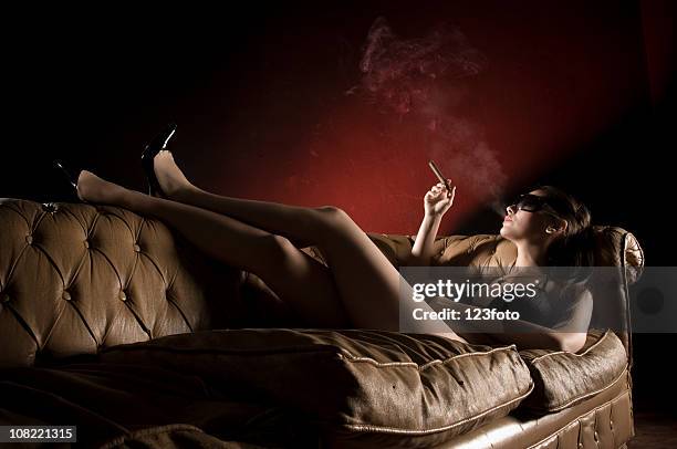 mujer joven relájese en la sala de estar con un sofá cama, para fumadores, para fumadores - beautiful women smoking cigars fotografías e imágenes de stock