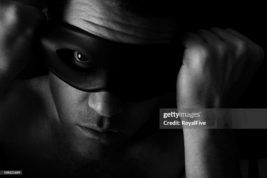 Man in the dark putting on a mask over his eyes