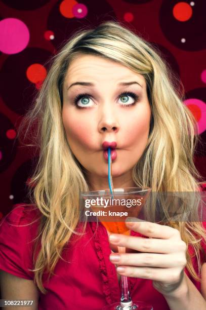 young woman sipping cocktail through straw - cross eyed 個照片及圖片檔