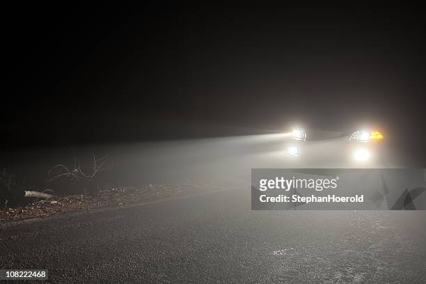 headlights of a car driving in the fog at night - foggy road stock pictures, royalty-free photos & images