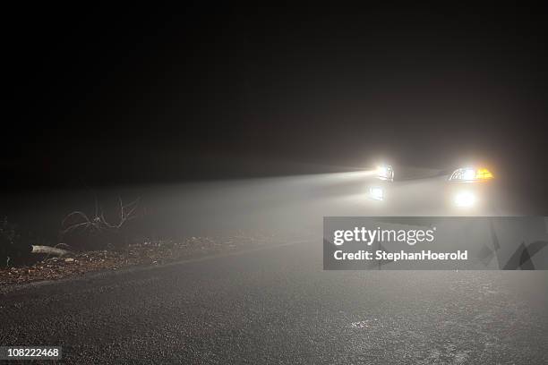 faróis de carro dirigindo na neblina à noite - farol luz de veículo - fotografias e filmes do acervo