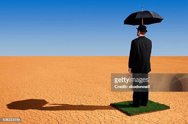 business man standing in the desert - holding umbrella stock pictures, royalty-free photos & images