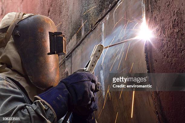 worker in protective gear welding new plates on ship's hull. - repairing boat stock pictures, royalty-free photos & images