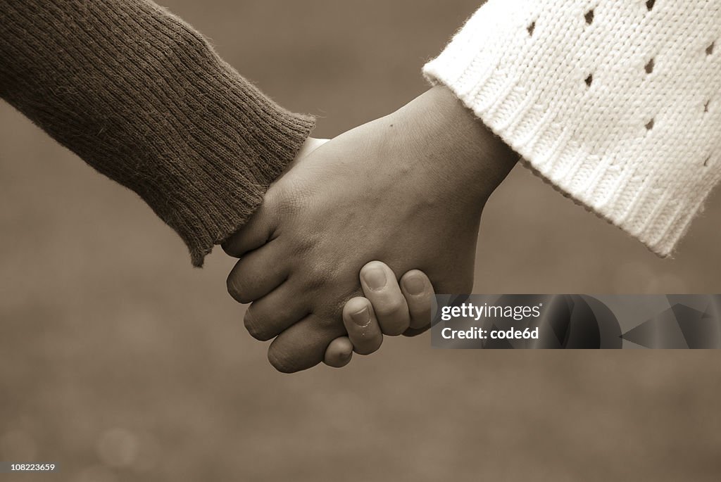 Diverse women couple holding hands, sepia toned