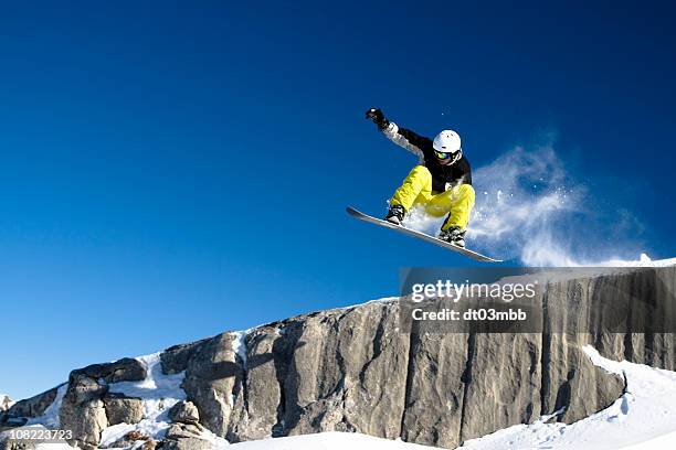snowboarder dropping off short cliff against blue sky - snowboard jump bildbanksfoton och bilder