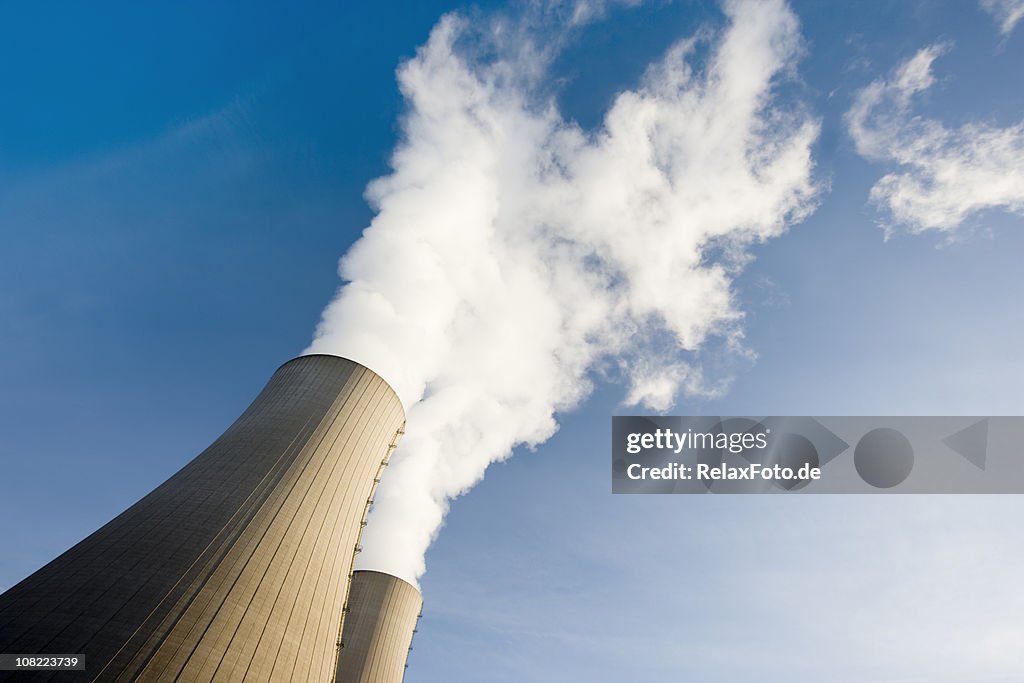 Tilt Shot of Two Steaming Cooling Towers with blue sky