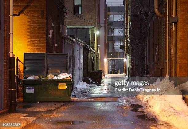 snowy and dark, grunge alley with lights shining at night - industrial bin stock pictures, royalty-free photos & images