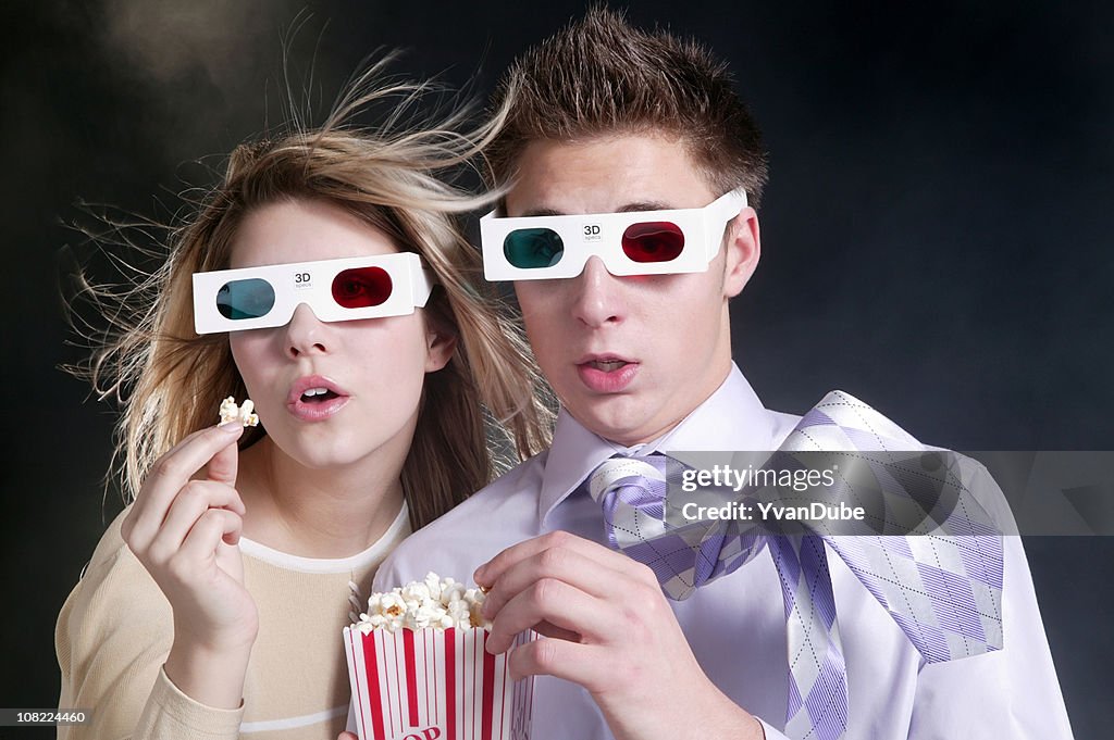 Young couple watching 3d movie with popcorn