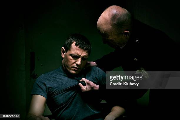 policeman grabbing man's tshirt during interrogation - interrogation stock pictures, royalty-free photos & images
