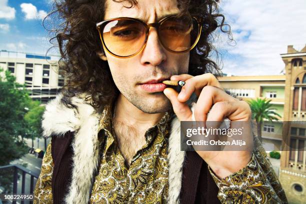 hippie man smoking marijuana cigarette outside - joint stockfoto's en -beelden