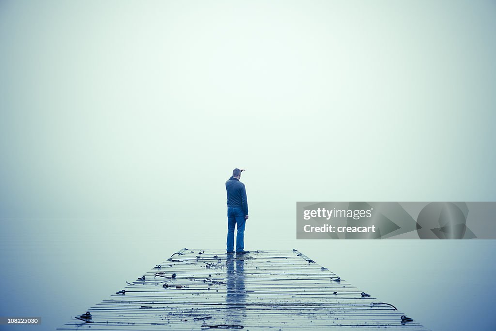 Hombre mirando a través de la niebla y de posicionarse el muelle