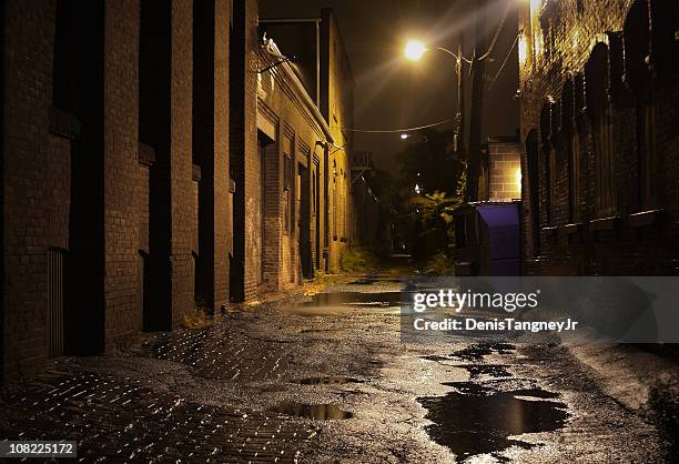urban alleyway con puddles por la noche - callejuela fotografías e imágenes de stock