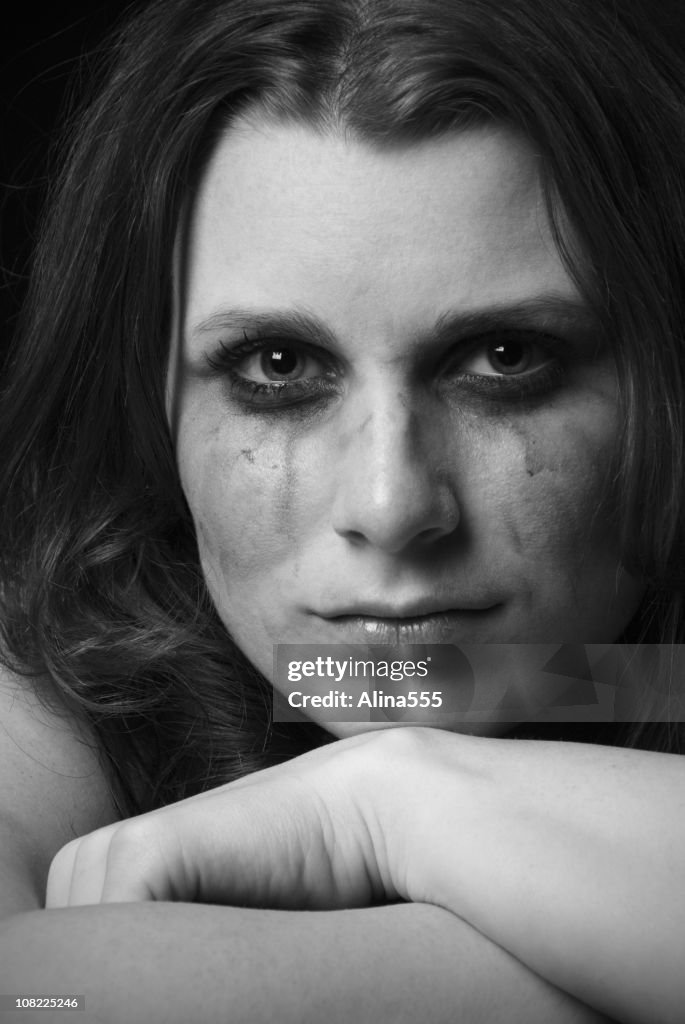 Sad womans face with strong and tough expression, smeared makeup