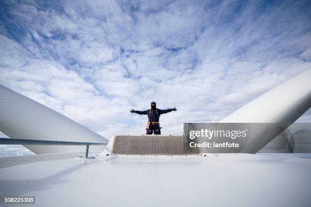 man with arms open at work on a giant wind turbine - turbine generator stock pictures, royalty-free photos & images