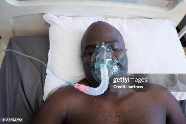 patient lies in hospital bed on a respirator - hospital ventilator stock pictures, royalty-free photos & images