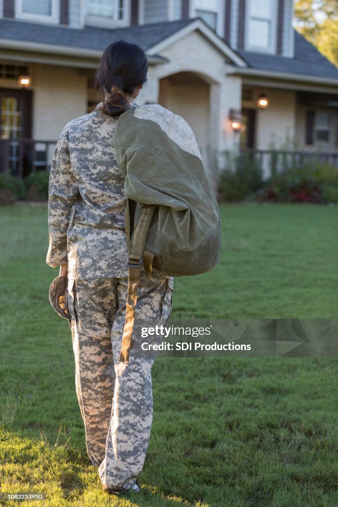 Female military officer looks longingly at house before tour of duty