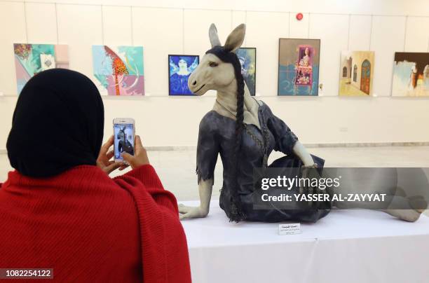 Kuwaiti woman takes a picture of a statue depicting "Hemarat al-Gayla" by Kuwaiti artist Bader al-Mansour at a gallery in Kuwait City on January 14,...
