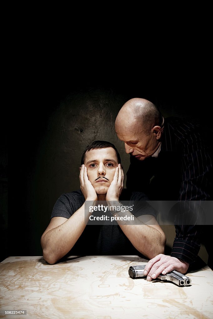 Man Looking Bored While Being Interrogated by Male Holding Gun