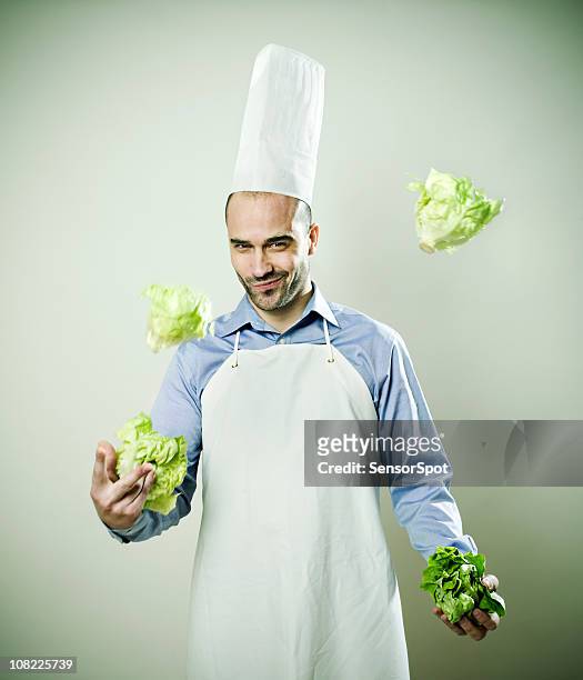 hombre joven chef malabarismo lechuga cabezales - action cooking fotografías e imágenes de stock