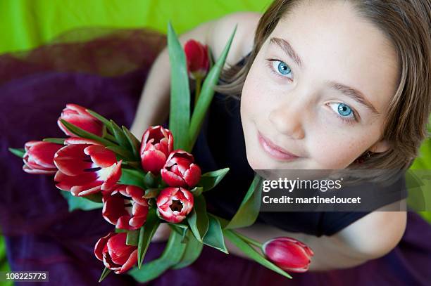young girl looking up with a tulip bouquet in hands. - innocuous stock pictures, royalty-free photos & images