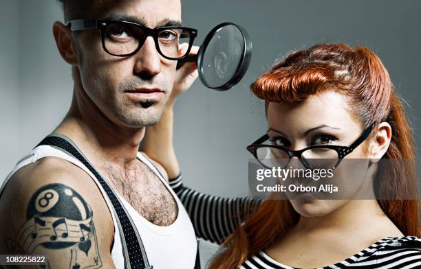 junges paar mit brille und hält lupe - rockabilly stock-fotos und bilder
