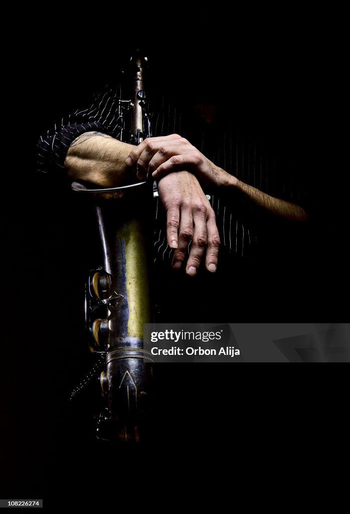 Homem braços de envolver Saxofone, baixo chave