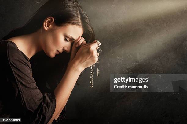 jovem mulher rezar com rosary - conta de rosário imagens e fotografias de stock