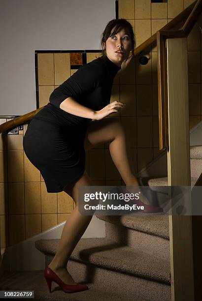 woman tiptoeing up the stairs - suspicion stock pictures, royalty-free photos & images