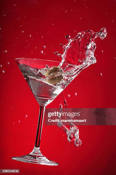 martini splashing on red background - splashing cocktail stock pictures, royalty-free photos & images