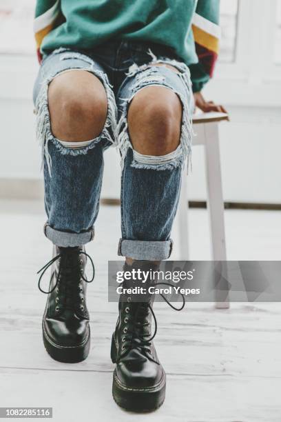 casual portrait of teenager in ripped jeans.low section - knees together 個照片及圖片檔