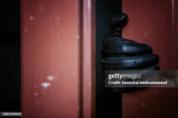 masked burglar with crowbar breaking and entering into a victim's home - image - burgler stock-fotos und bilder