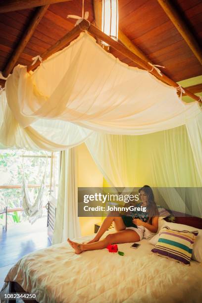 beautiful woman reading on bed in hotel room - trancoso stock pictures, royalty-free photos & images