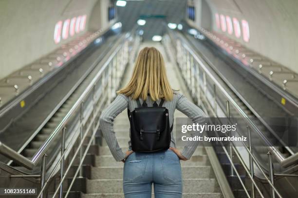 frau auf rolltreppe in u-bahn-station - stufen und treppen stock-fotos und bilder