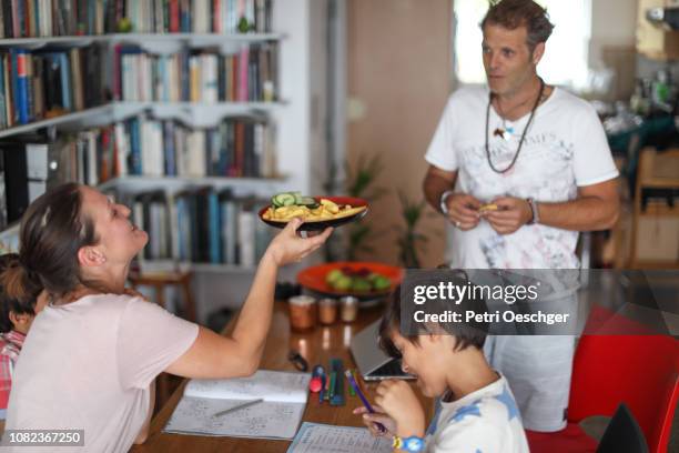 a family snacking on potato chips while sitting around the table at home. - family eating potato chips imagens e fotografias de stock