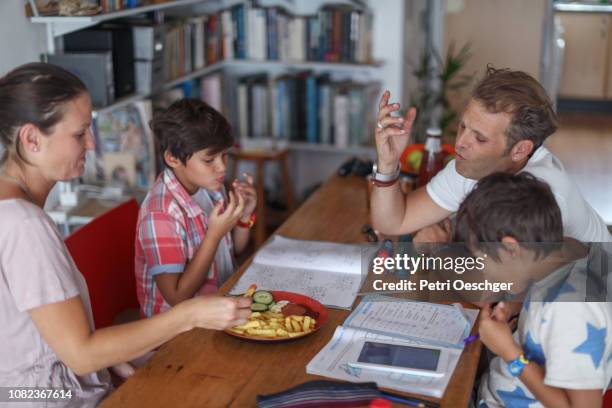 a family snacking on potato chips while sitting around the table at home. - family eating potato chips imagens e fotografias de stock