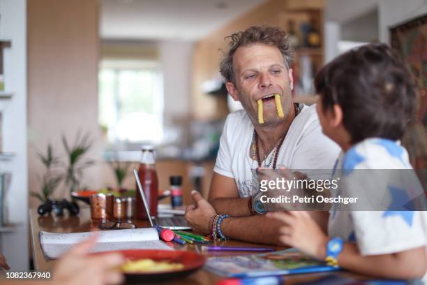 a family snacking on potato chips while sitting around the table at home. - zustand stockfoto's en -beelden