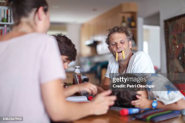 a family snacking on potato chips while sitting around the table at home. - family eating potato chips imagens e fotografias de stock