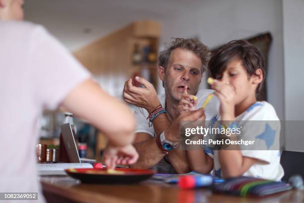 a family snacking on potato chips while sitting around the table at home. - family eating potato chips imagens e fotografias de stock